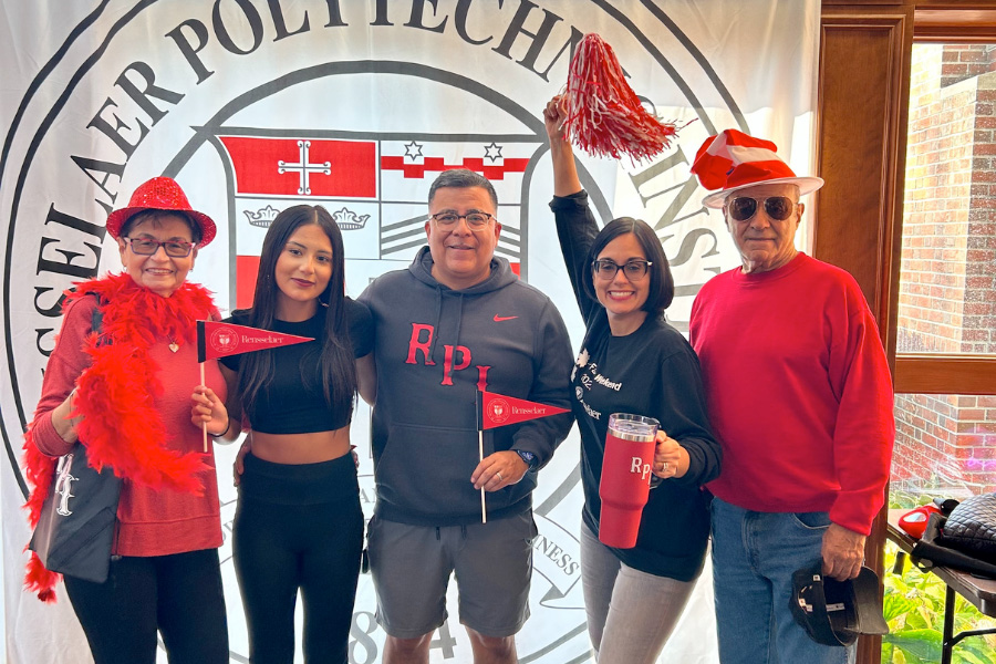 Family of five poses in front of the RPI seal with pom poms and RPI flags