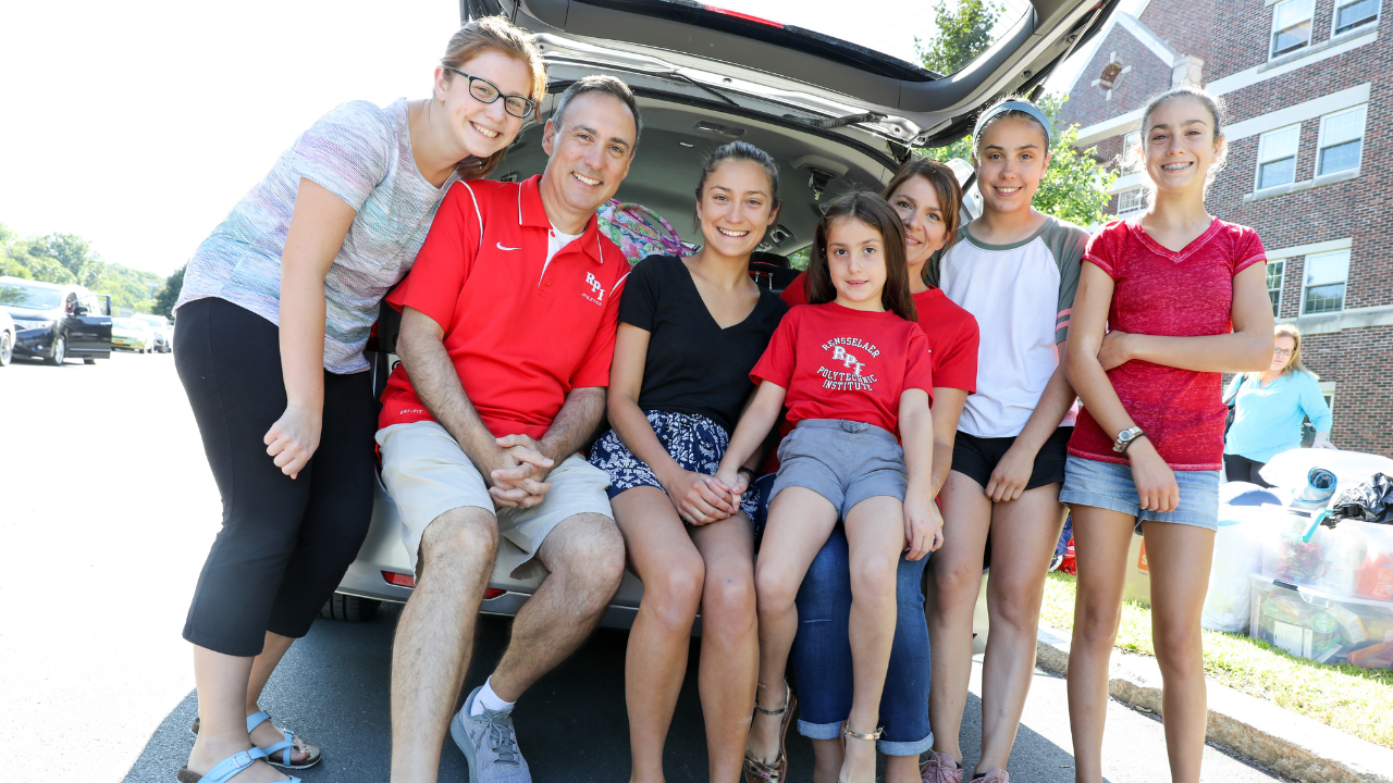 Family posing behind a car